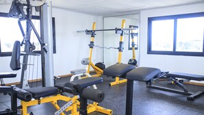 A gym with weightlifting equipment, benches, and a mirrored wall. - Sunset Inn Guest House (Monrovia)