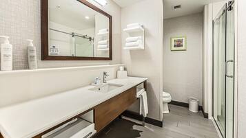 Une salle de bain moderne dotée d’un grand miroir, de deux vasques et d’une douche à parois de verre.