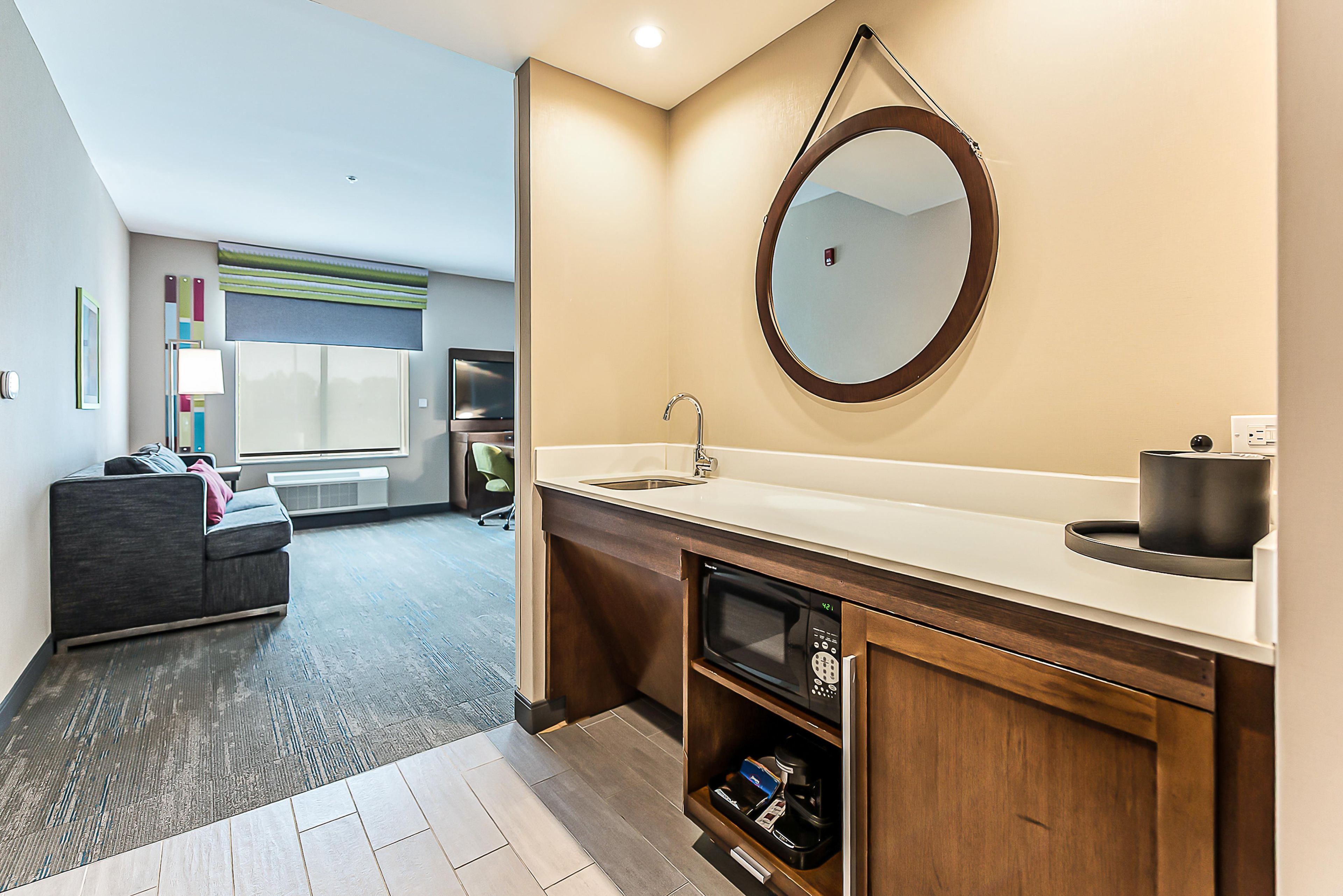 A modern bathroom with a sink, mirror, and built-in microwave.