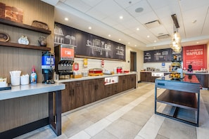 Interior de una cafetería moderna con detalles de madera, un menú en una pizarra y una barra con diferentes productos alimenticios.