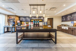 A modern kitchen area with a central island, overhead pendant lights, and a chalkboard menu. - Hampton Inn & Suites Howell (Howell)
