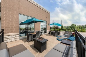 An outdoor patio with seating, a fire pit, and umbrellas.
