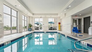 A swimming pool with clear water, a lifeguard chair, and a blue chair near the poolside.