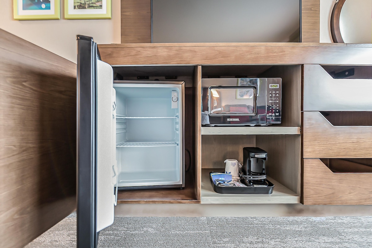 A compact kitchenette with a microwave, coffee maker, and a refrigerator.