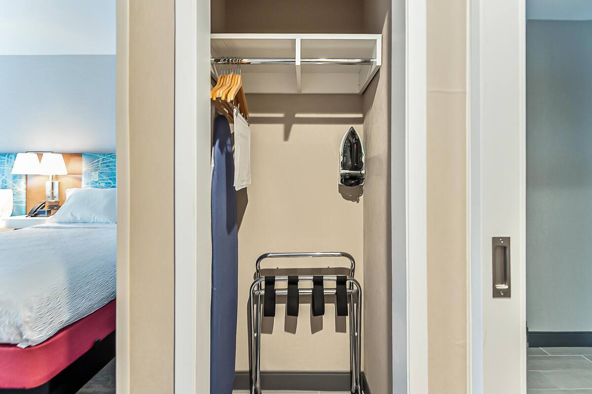 Quarto de hotel com cama, um cabideiro de cortina de chuveiro e um porta-toalhas.