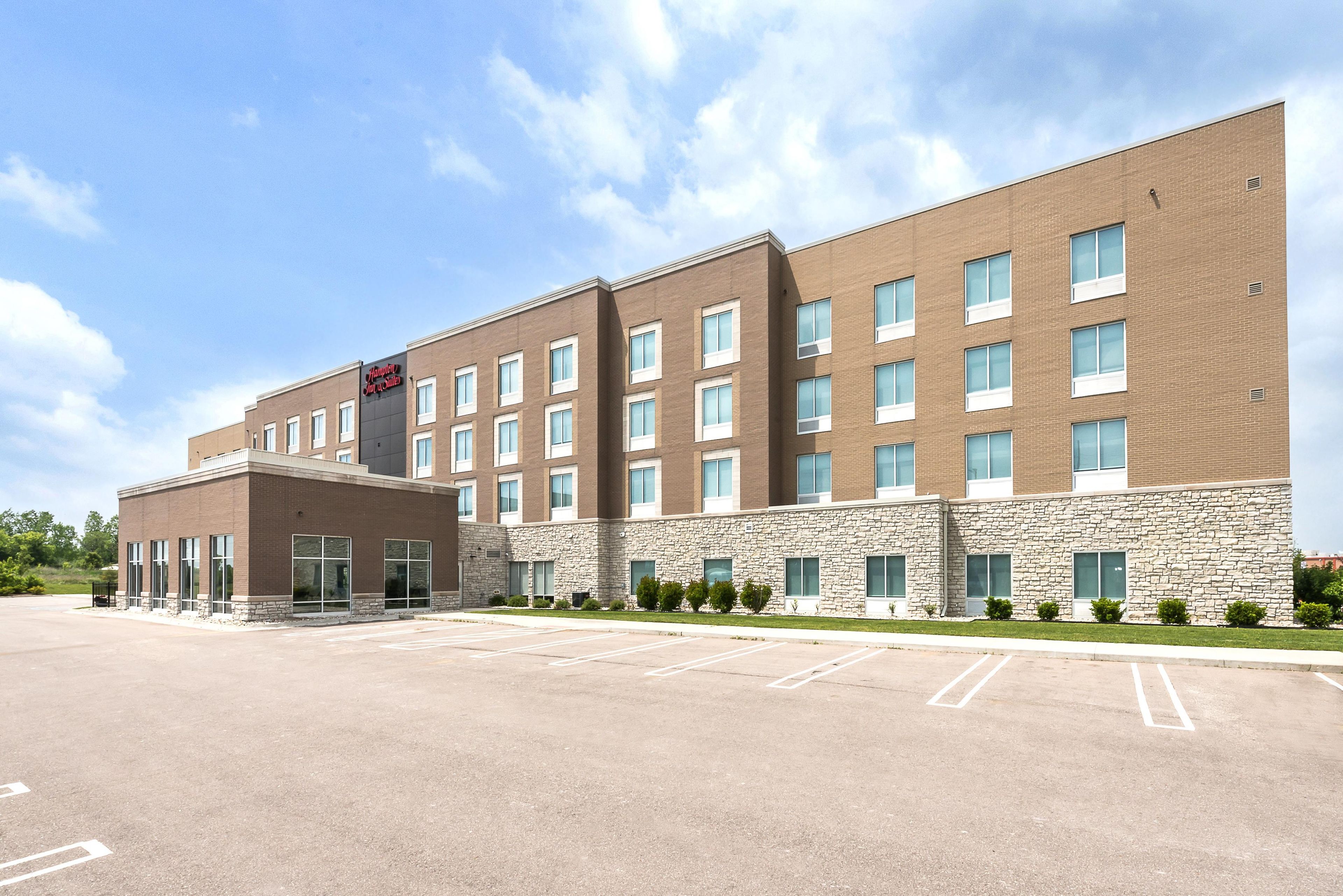 A multi-story hotel with a brick facade, large windows, and a parking lot.