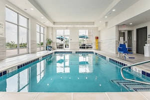 Una piscina con agua cristalina, una silla de salvavidas y un sillón azul cerca de la orilla.