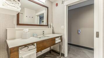 Un baño moderno con un lavamanos blanco, tocador de madera y un espejo grande.
