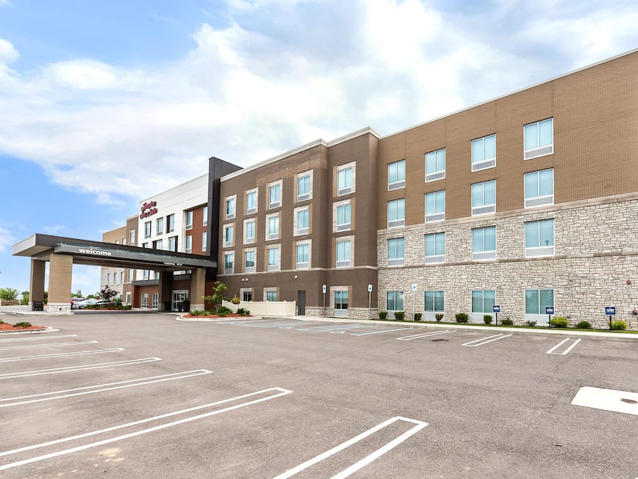 A modern hotel with a brick facade, multiple windows, and a spacious parking lot.