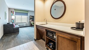 A modern bathroom with a sink, mirror, and built-in microwave.