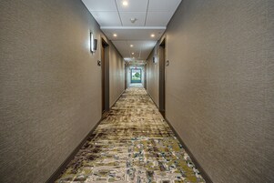 Un pasillo largo y estrecho con alfombra estampada y paredes color crema.