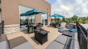 An outdoor patio with seating, a fire pit, and umbrellas.