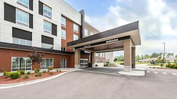 A modern building with a 'welcome' sign, large windows, and a landscaped entrance area.