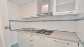 A kitchen with white cabinets, a gas stove, and a stainless steel sink. - Residence a Palinuro ID 559 (Palinuro)