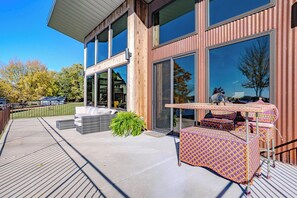 A modern building with large windows, a covered patio with outdoor furniture, and a view of the surrounding area. - Lake + Ledge Retreat l Modern Luxury Home on Pike Lake (Hatley)