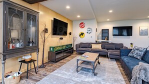 A modern living room with a large cabinet, a sofa, a coffee table, and a TV mounted on the wall. - Lake + Ledge Retreat l Modern Luxury Home on Pike Lake (Hatley)