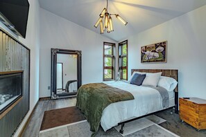 A bedroom with a large bed, a mirror, a painting, and a wooden dresser. - Lake + Ledge Retreat l Modern Luxury Home on Pike Lake (Hatley)