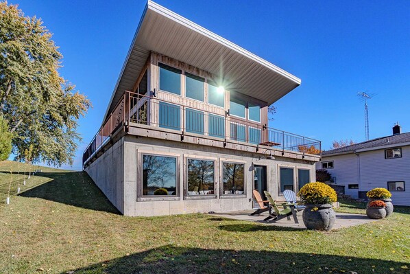 A modern two-story house with a balcony, large windows, and potted plants. - Lake + Ledge Retreat l Modern Luxury Home on Pike Lake (Hatley)