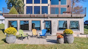 A modern two-story house with large windows, a balcony, and outdoor seating. - Lake + Ledge Retreat l Modern Luxury Home on Pike Lake (Hatley)