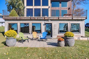 A modern two-story house with large windows, a balcony, and outdoor seating. - Lake + Ledge Retreat l Modern Luxury Home on Pike Lake (Hatley)
