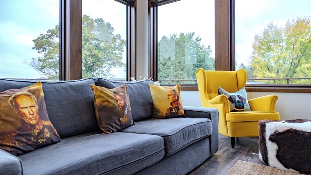 A modern living room with a grey sofa, yellow armchair, and a brown and white ottoman. - Lake + Ledge Retreat l Modern Luxury Home on Pike Lake (Hatley)
