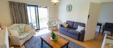 Een woonkamer met een bank, twee fauteuils, een salontafel en een vloerkleed.