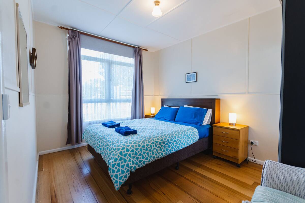 A bedroom with a bed, nightstands, a lamp, and a window with curtains.