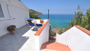 A staircase leading to a terrace with a view of the sea, a white building, and a blue sunshade. - Residence a Palinuro ID 128 (Palinuro)