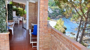 A balcony with a brick wall, a blue chair, and a table. - Residence a Palinuro ID 126 (Palinuro)