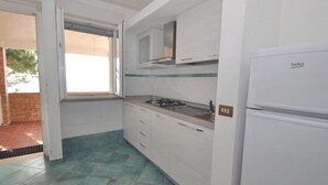 A compact kitchen with white cabinets, a gas stove, and a white refrigerator. - Residence a Palinuro ID 127 (Palinuro)