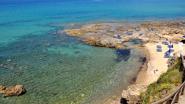 A coastal beach with clear waters, rocky formations, and blue lounge chairs. - Residence a Palinuro ID 127 (Palinuro)