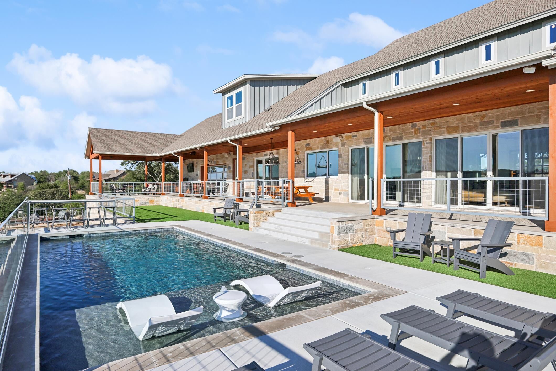 A modern house with a swimming pool, outdoor seating, and a covered patio area.