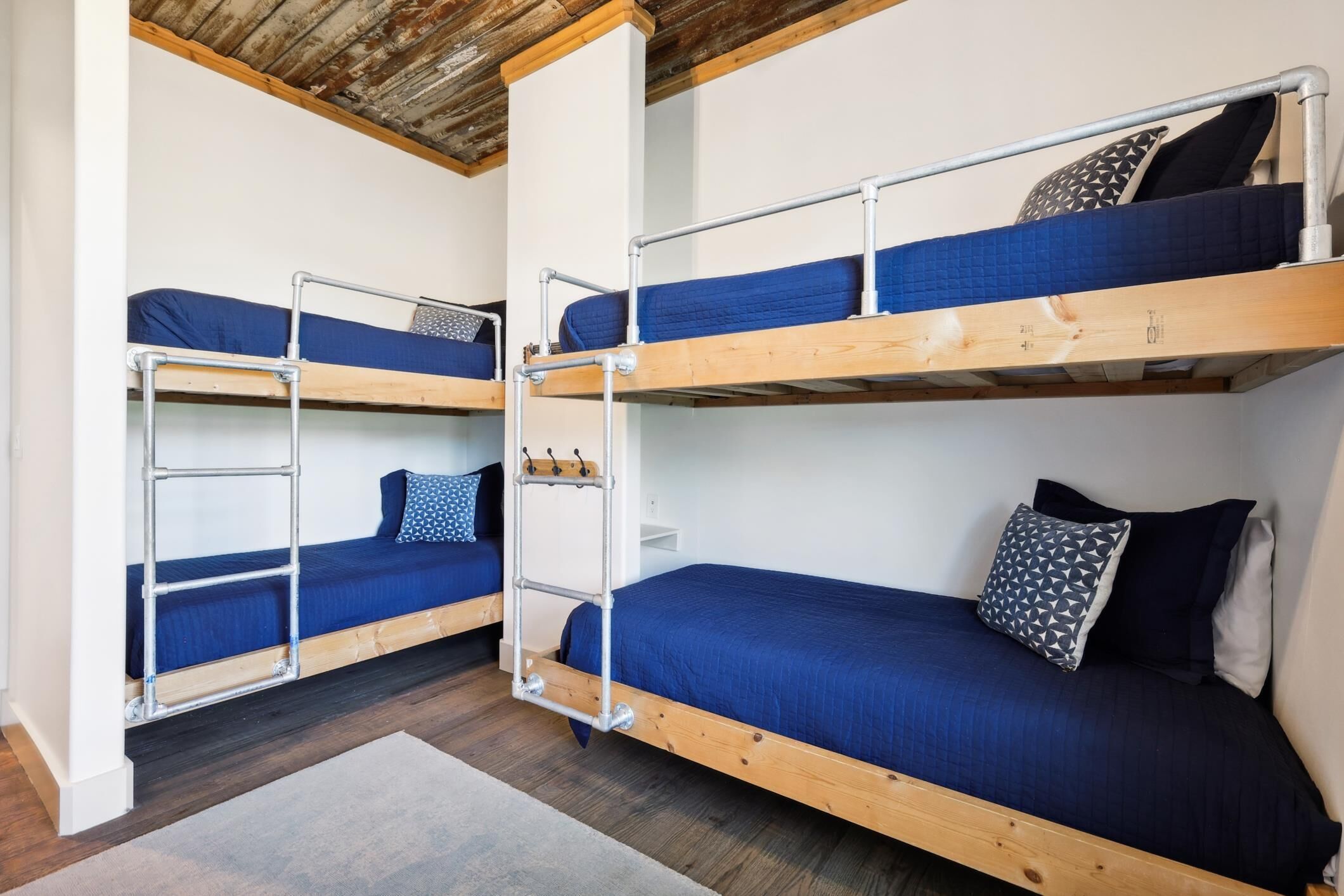 Un dormitorio con dos literas, cada una con una escalera metálica, y un pequeño estante blanco.