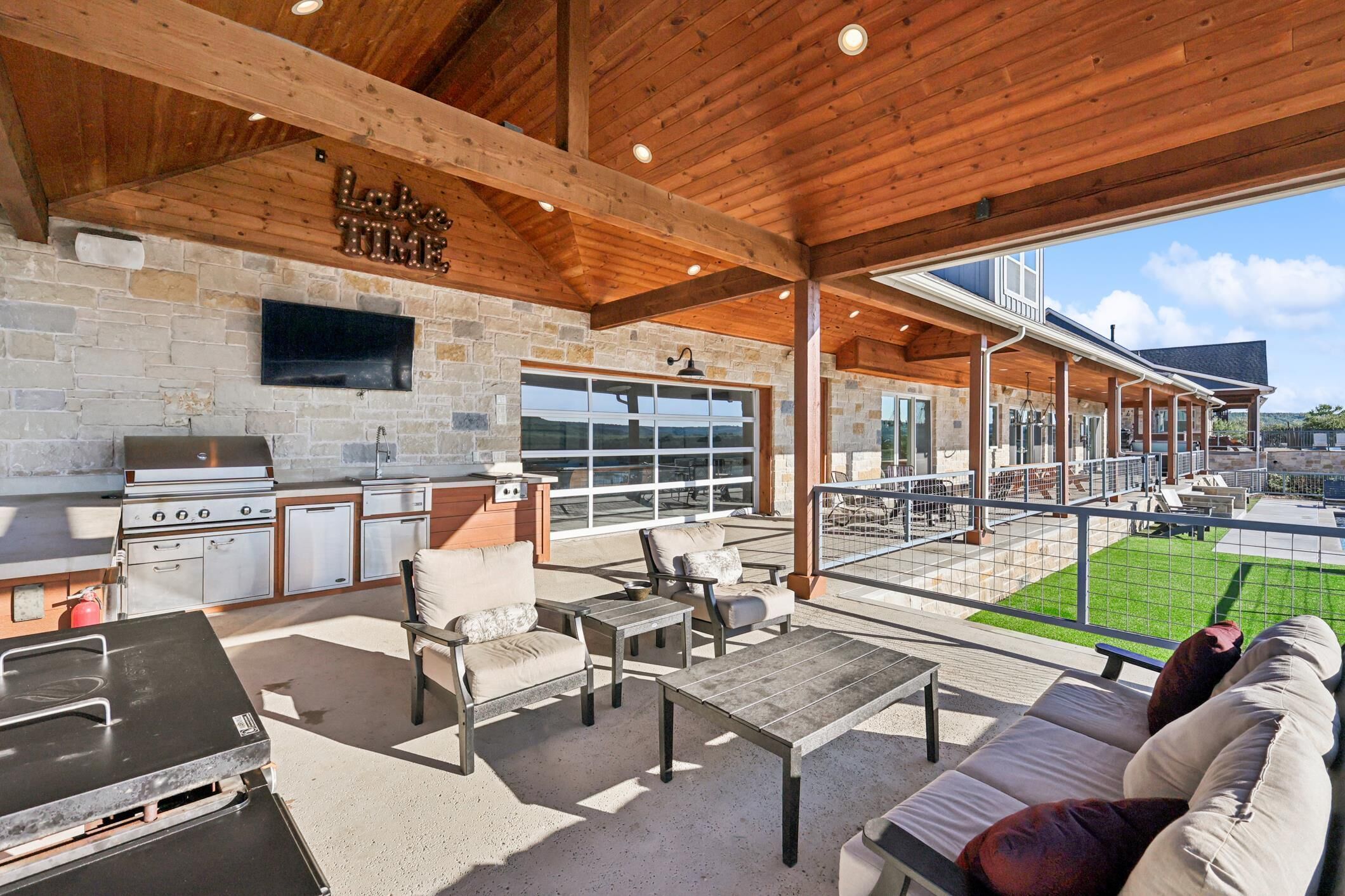 An outdoor patio with a stone fireplace, grilling area, and seating.