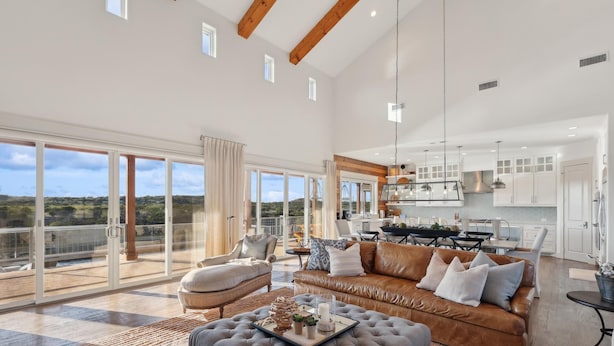 A spacious living area with a large sofa, ottoman, and a dining table. - PK LakeTime: 6 Bedroom/ 4 Bath Home with Dock, pool/hot tub, and game room (Strawn)