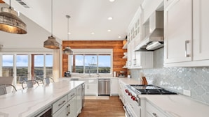 A modern kitchen with white cabinetry, a large island, and a view of the landscape. - PK LakeTime: 6 Bedroom/ 4 Bath Home with Dock, pool/hot tub, and game room (Strawn)