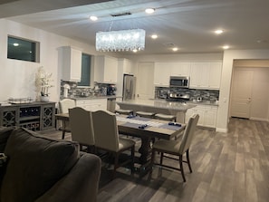A modern kitchen with white cabinets, a central island, and a chandelier.