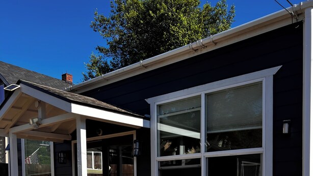 A house with a covered porch, two wooden chairs, and a table. - Very clean house with amazing park across the street and Japanese garden. (Coos Bay)