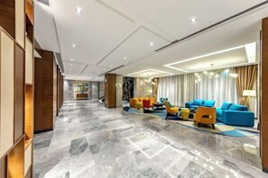 A modern lobby with a marble floor, a reception desk, and a seating area with colorful sofas. - Hampton by Hilton Lijiang Old Town (Lijiang)