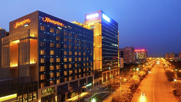Un hotel con un llamativo letrero de 'Hampton', varios pisos y una fachada bien iluminada.