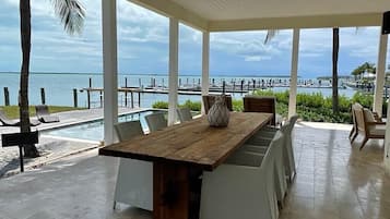 Un espace extérieur abrité où l’on peut prendre ses repas, avec vue sur le port de plaisance et l’eau.