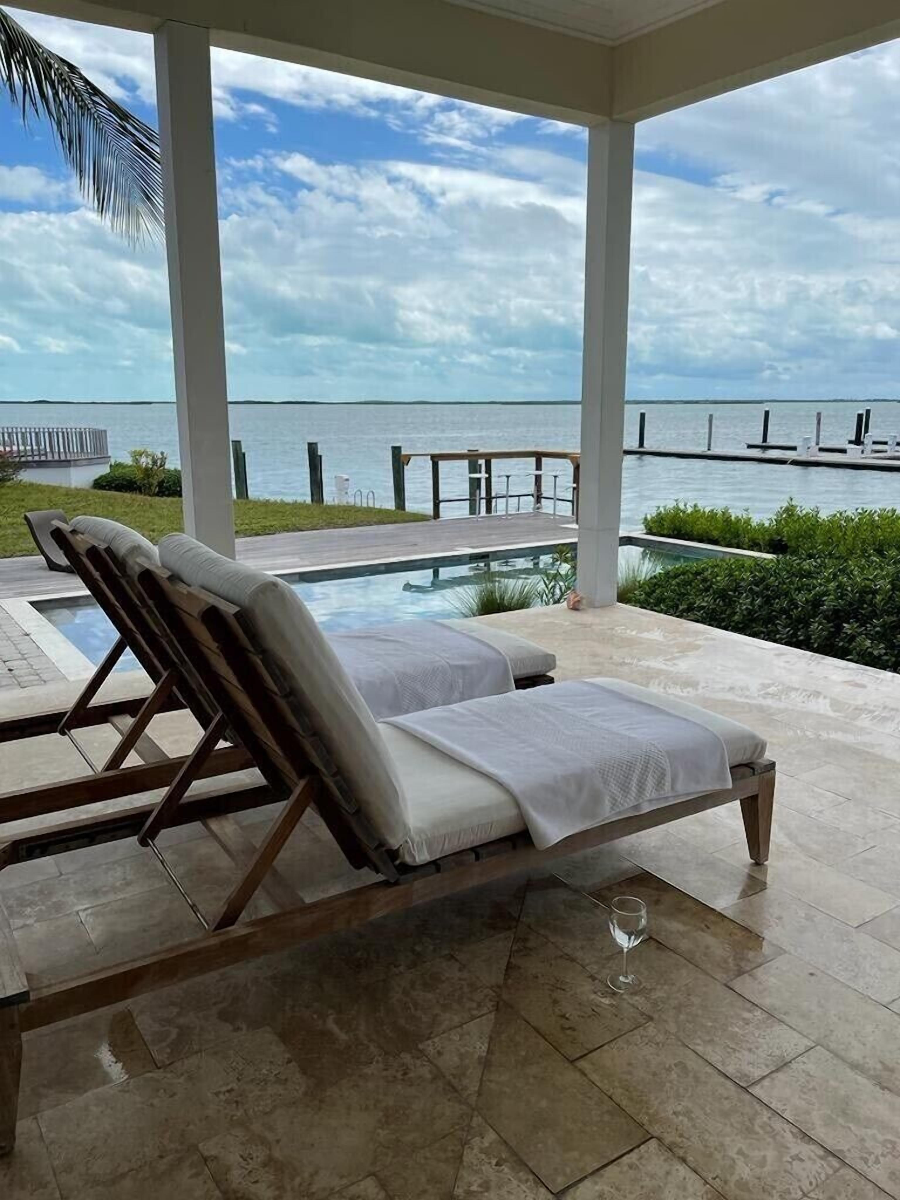Un espace extérieur abrité avec une piscine, deux chaises longues et une vue sur la mer.