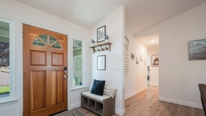 A hallway with a wooden door, a bench, a small shelf with hooks, and a framed quote on the wall. - The Sunset Ranchette : Luxury Paso Robles Getaway! (Paso Robles)