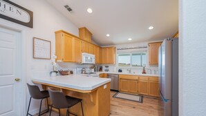 A kitchen with wooden cabinets, a stainless steel refrigerator, and a white countertop. - The Sunset Ranchette : Luxury Paso Robles Getaway! (Paso Robles)