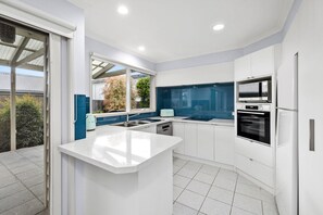 Una cocina moderna con armarios blancos, una isla central, horno empotrado y lavavajillas.