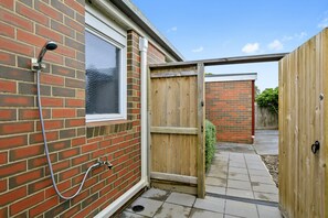 Una casa de ladrillo con una puerta de madera, una ventana y una manguera conectada a la pared.