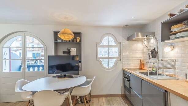 A modern kitchen with a dining area, large windows, and a TV. - Appartement Odyssée - Welkeys (Megève)