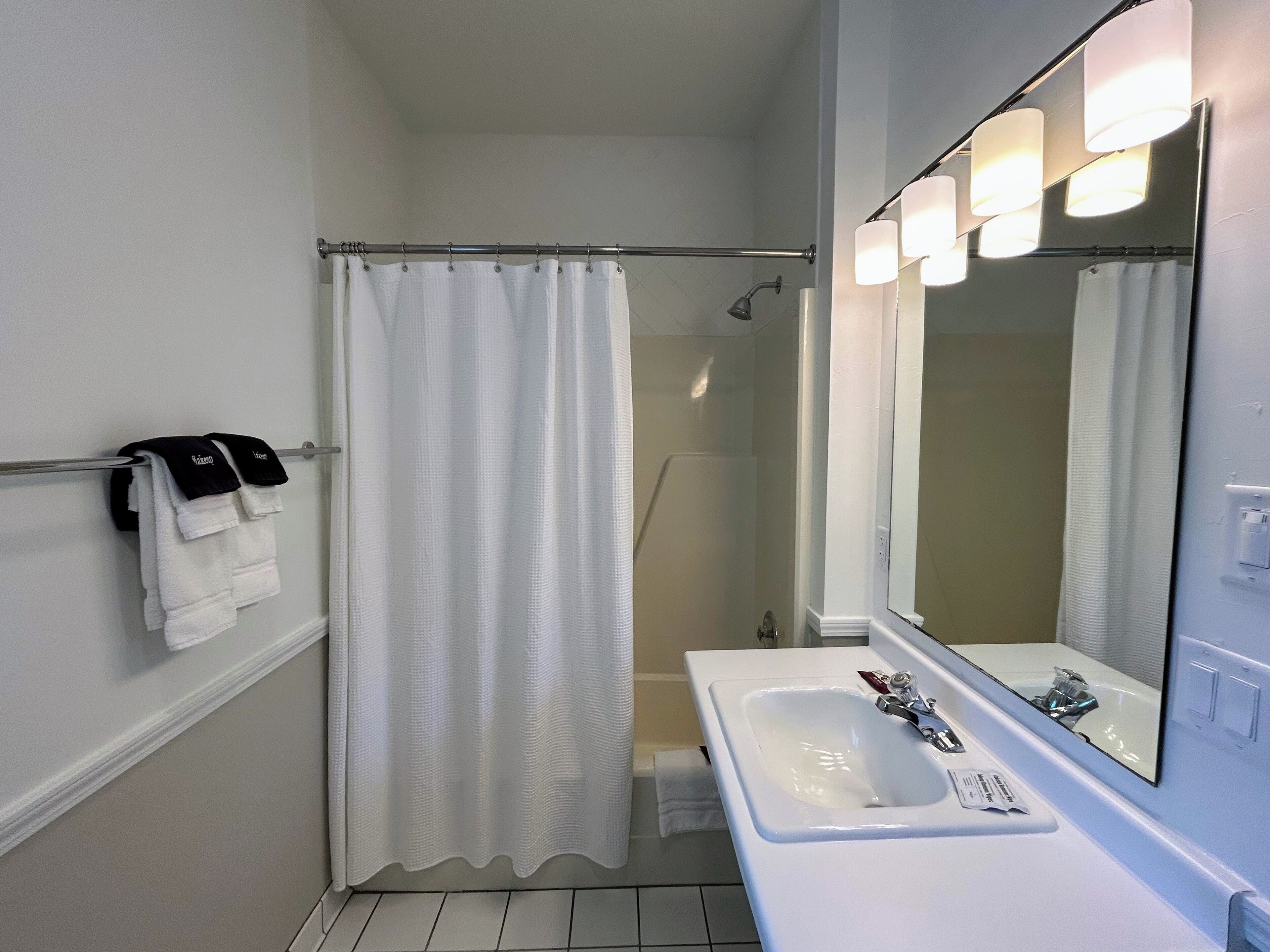 Un baño con ducha, lavamanos y espejo.