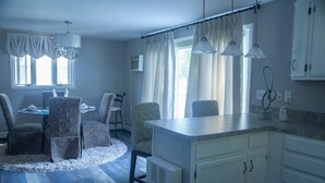 Une cuisine moderne avec des meubles blancs, un îlot central et des luminaires suspendus.