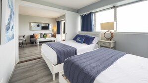 Une chambre d’hôtel avec deux lits, un bureau, une chaise, un miroir et une fenêtre avec des rideaux.